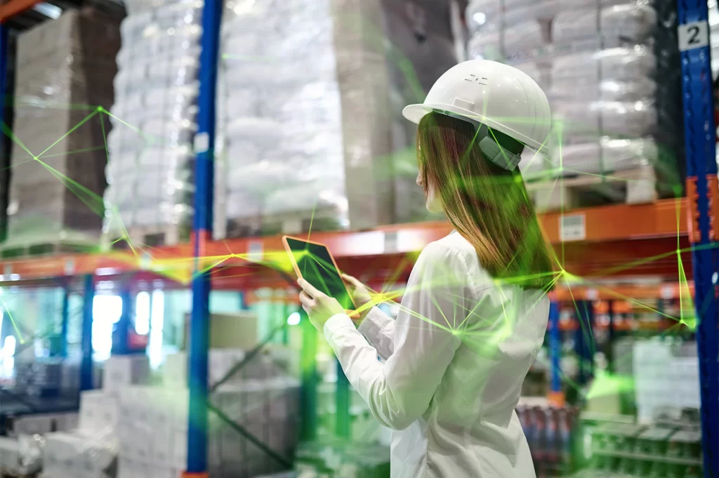 woman with hard hat walking in a warehouse with a tablet and a green plexus overlayed