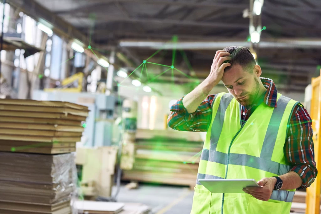 factory worker holding head looking at tablet with green plexus overlayed