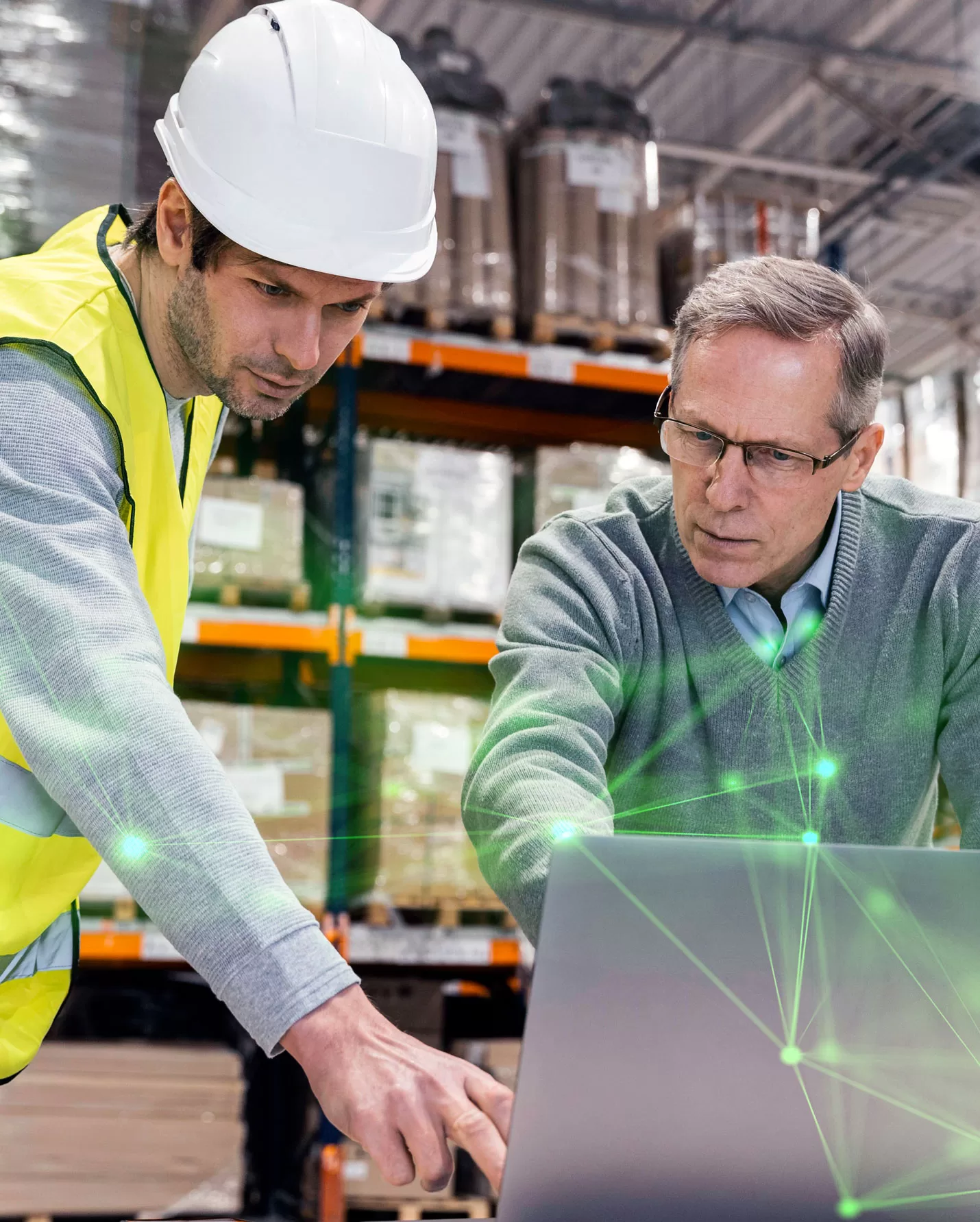 men in warehouse looking at laptop with green plexus overlayed