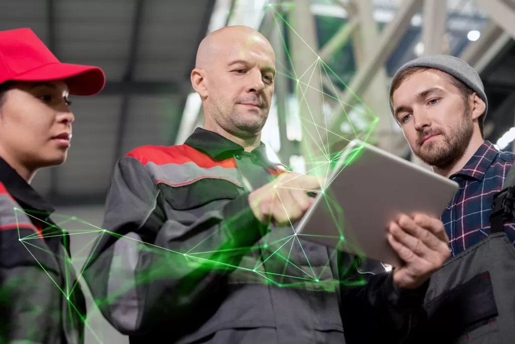 Fleet manager standing around colleagues showing them tablet with green plexus overlayed