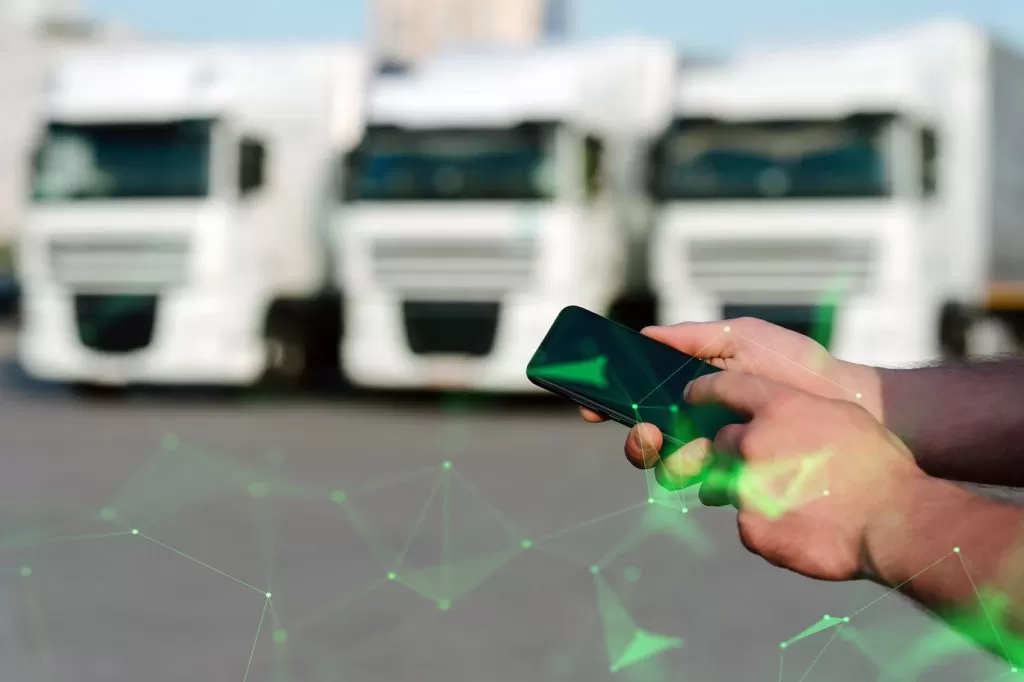 Lorry fleet in background with hands holding phone in foreground