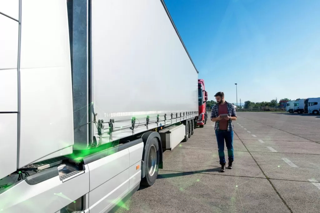 truck driver inspecting vehicle trailer tires before driving green plexus