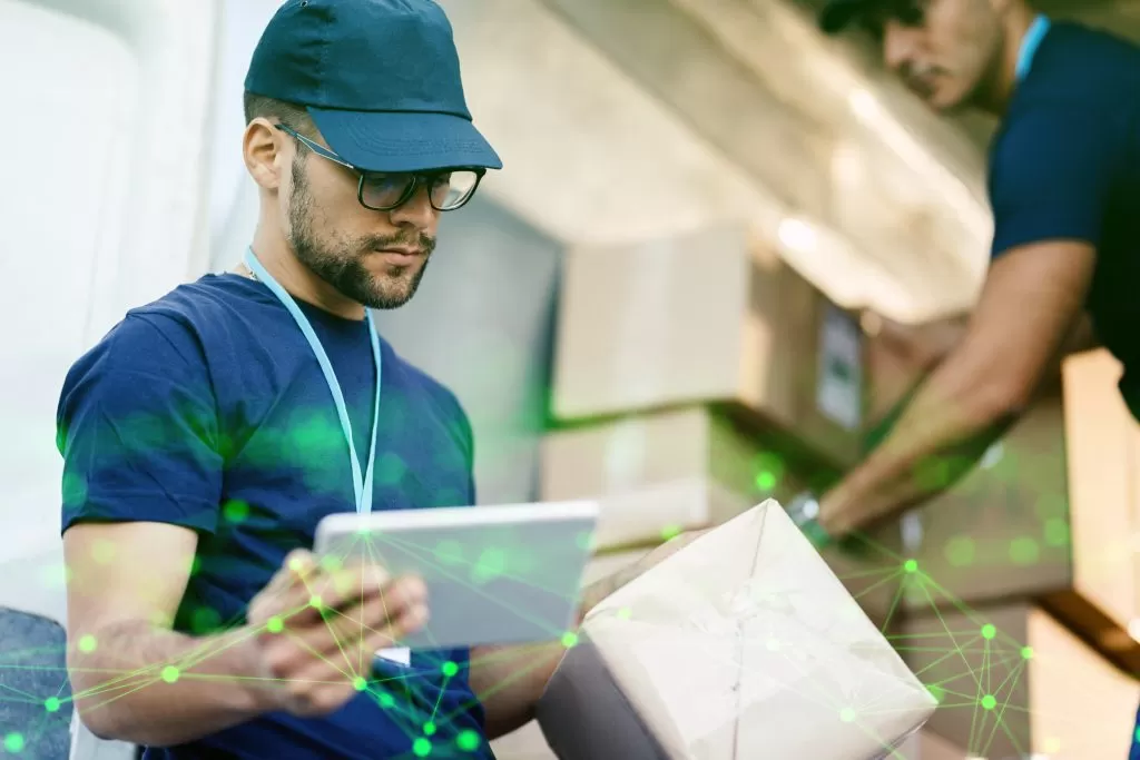 young delivery man using touchpad while reading label package green plexus