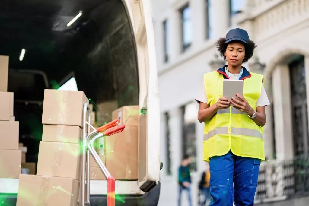 delivery driver using digital tablet while unloading packages from van green plexus