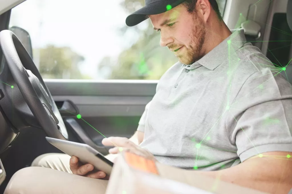 delivery driver in van using transport app on device with green plexus overlay