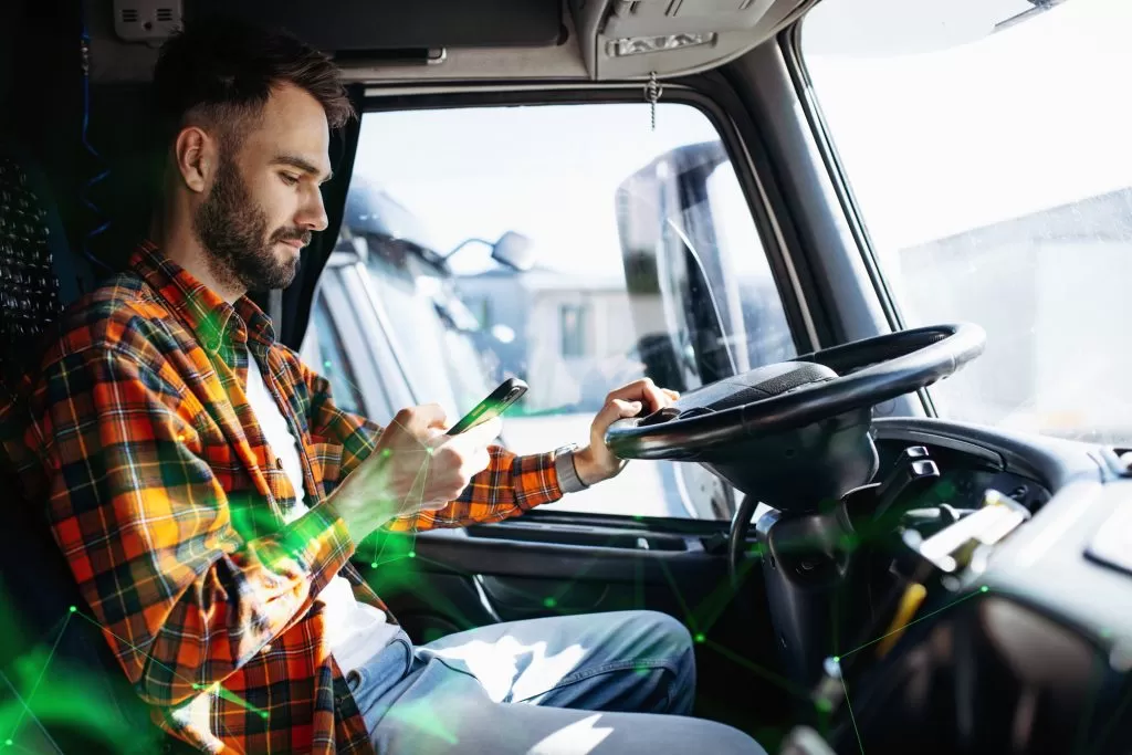 male truck driver using transport app on mobile device inisde truck with green plexus overlay